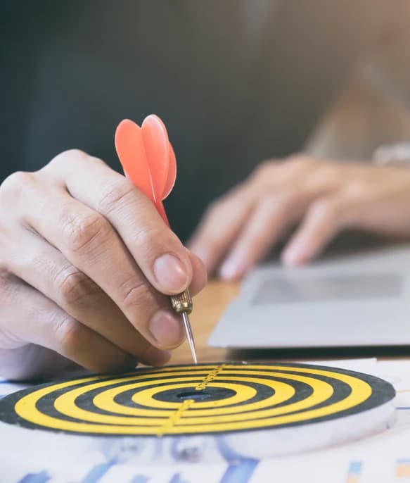 Hand aiming a dart at a target